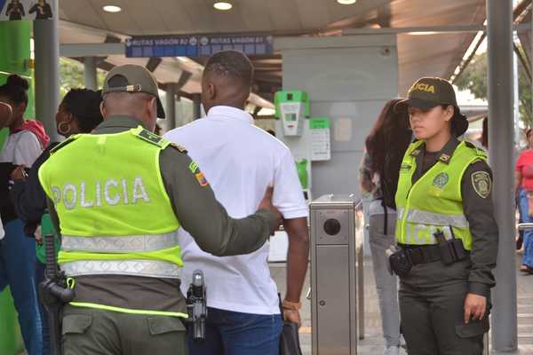 Dos policías requisan a personas a la entrada de las estaciones del MIO