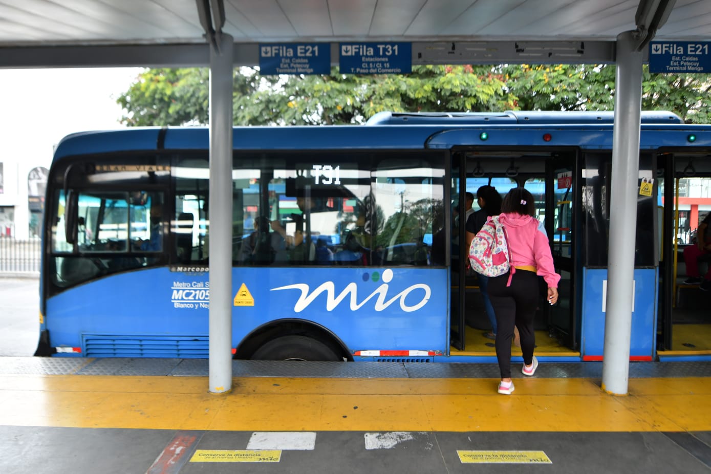 Bus del MIO T31 en una estación, tiene las puertas abiertas y los pasajeros están abordándolo.