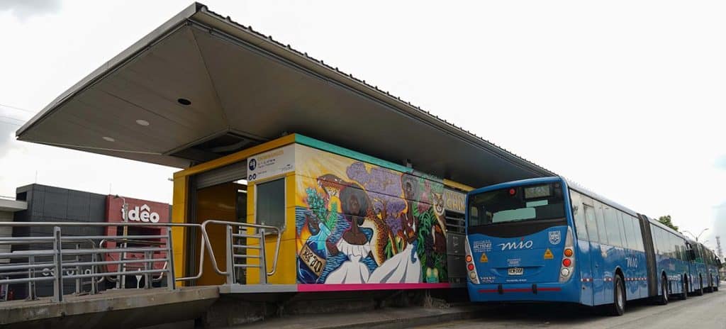 Bus del MIO visto desde la parte trasera, está saliendo de la estación de chiminangos, se alcanza a observar el mural biopacífico