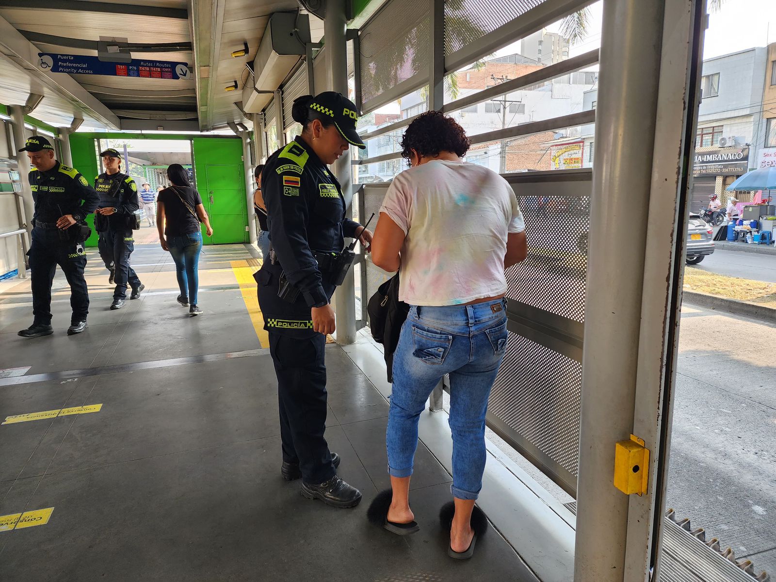 Foto de una agente de policía en una estación del MIO haciendo requisa a una usuaria.