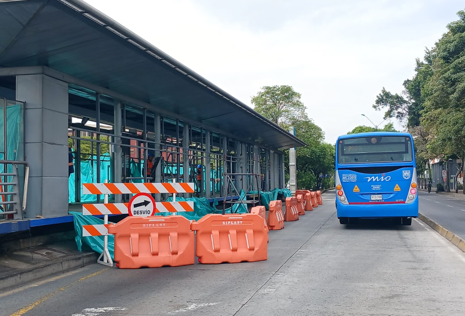 Foto de estación del MIO en reparación. También se encuentra vehículo del sistema sobre el carril solo bus.