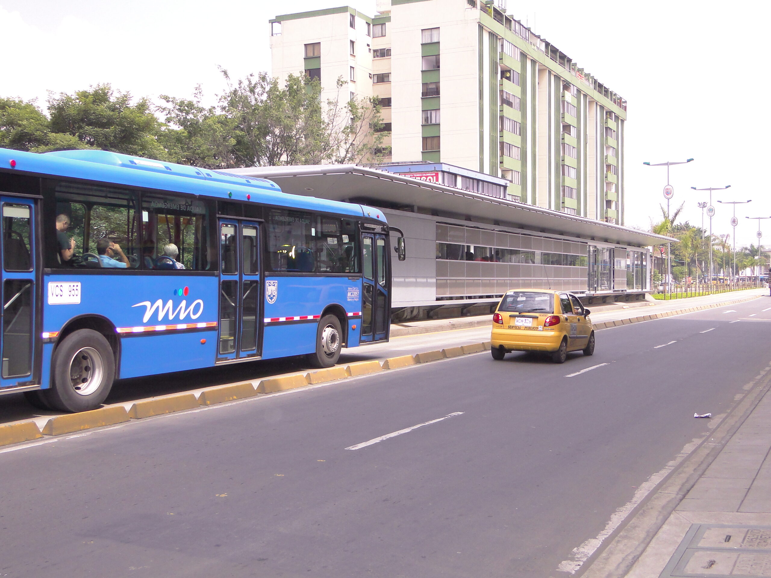 Foto en la cual se ve el carril mixto de la Avenida de la Américas y en el un taxi. Así mismo, en el carril solo bus un vehículo del MIO y la estación Américas.