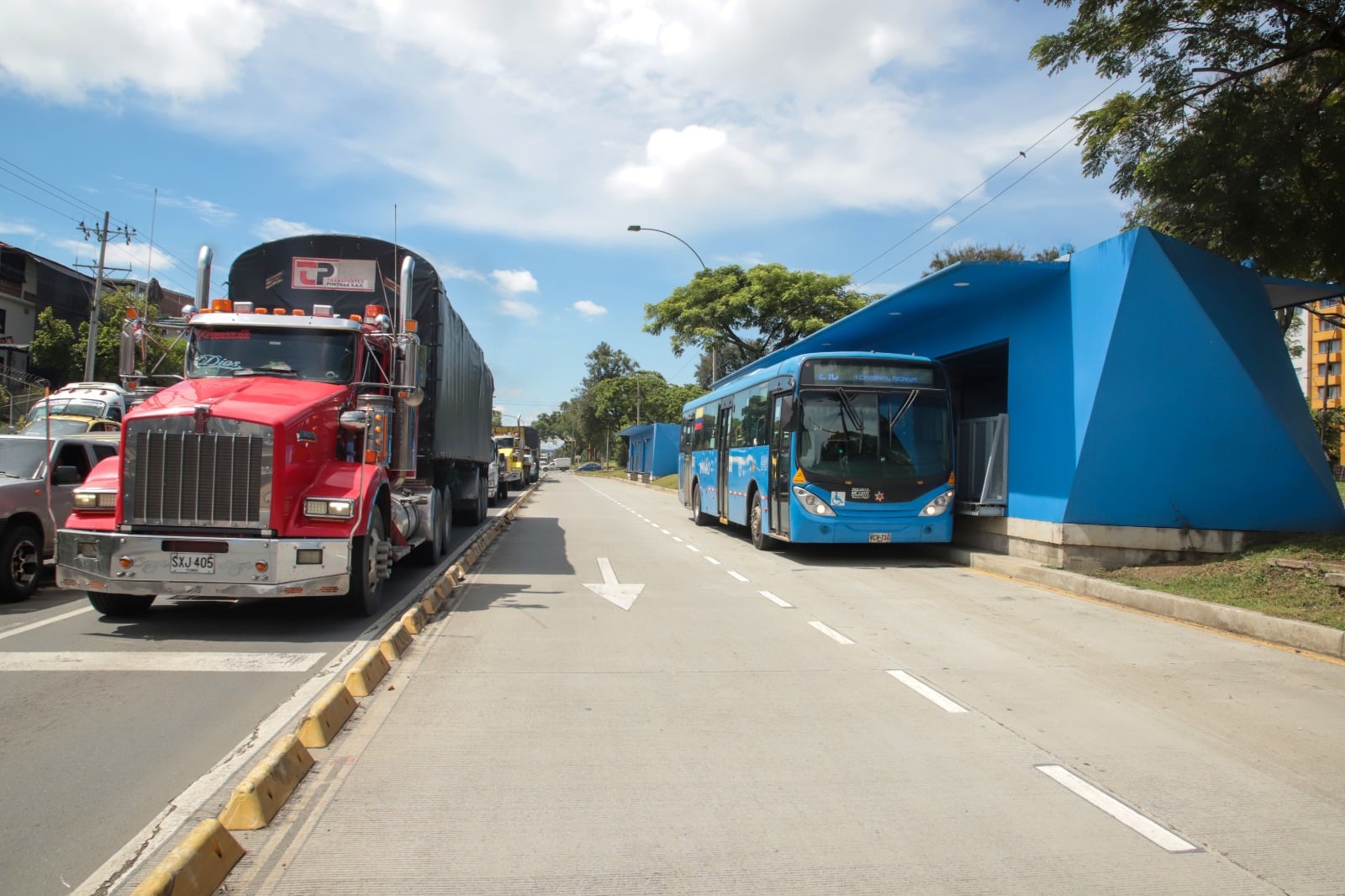 Foto en la cual se ve una estación de la Troncal Oriental donde está un bus del MIO y al lado el carril mixto donde se ve un camión.