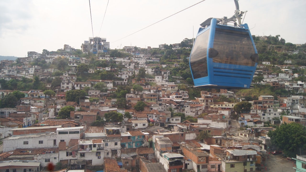 Foto donde se ve una cabina del MIO Cable en operación y abajo se ven las casas de Siloé.